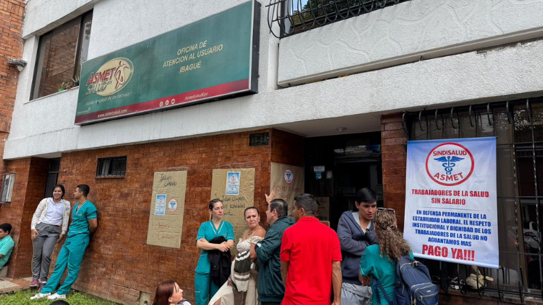 Trabajadores reunidos frente a una sede de Asmet Salud durante una protesta por estabilidad laboral y pagos.
