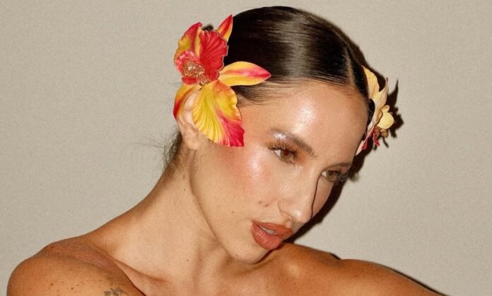 Aria Vega posa con flores tropicales en el cabello en una imagen promocional de la canción ‘Chévere’.