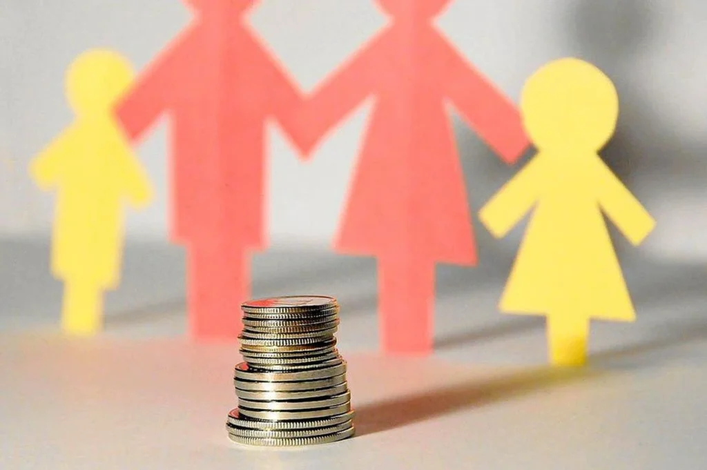 Monedas frente a figuras de familia en imagen alusiva a cuota alimentaria