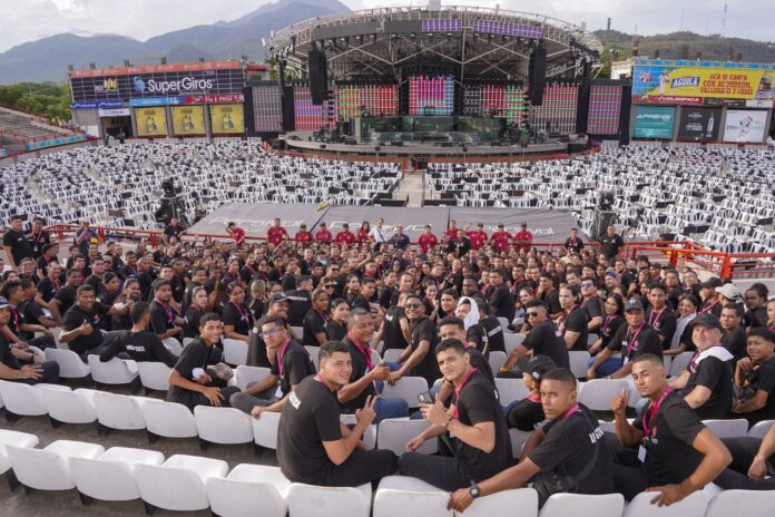 Cientos de jóvenes del equipo de logística del Festival Vallenato, uniformados de negro, posan en las gradas del Parque de la Leyenda Vallenata antes de un evento.