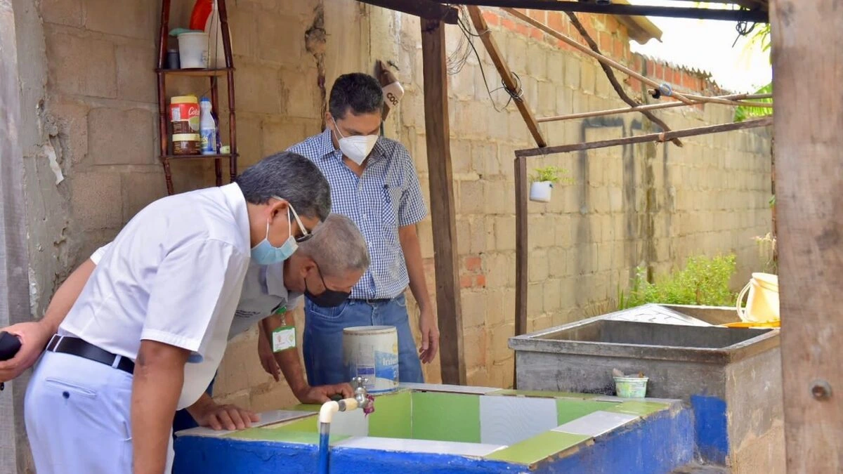 Funcionarios de la Secretaría de Salud de Valledupar realiza control larvario en un tanque de agua azul en una vivienda, buscando criaderos de mosquitos.