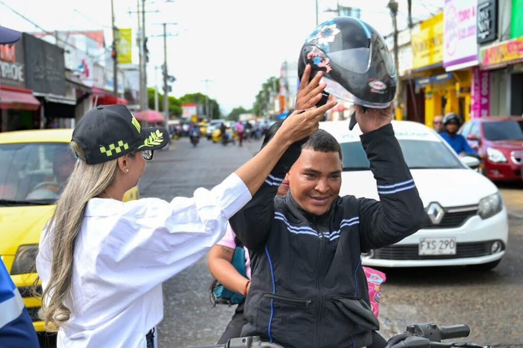 Agente de tránsito ayudando a motociclista a colocarse el casco en Valledupar