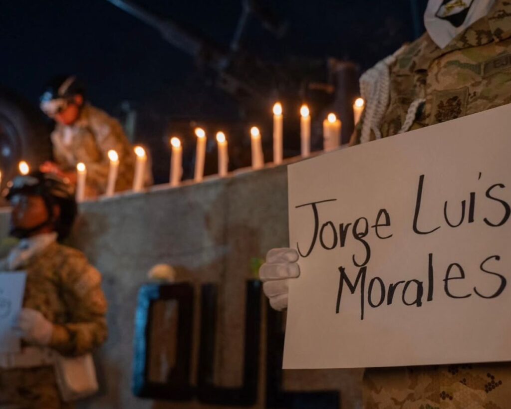 Homenaje a víctimas del accidente del avión Hércules C-130 con velas y cartel con nombre de fallecido.