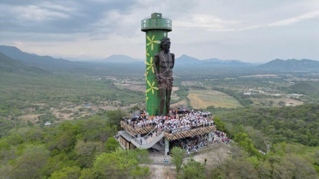 Fotografía aérea del monumento al Ecce Homo en la cima del cerro, rodeado de vegetación y con una multitud de visitantes vestidos de blanco.