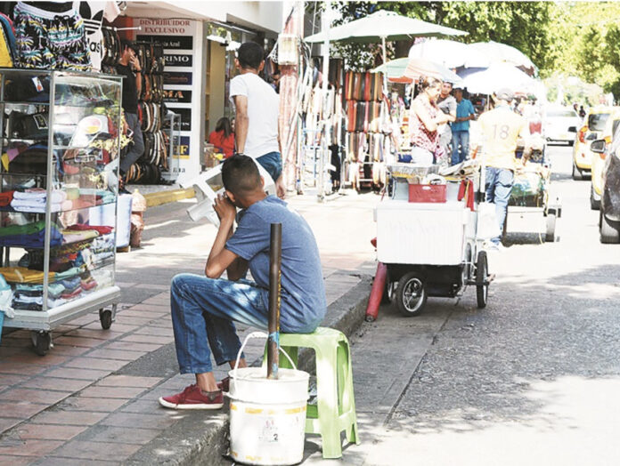 Vendedores informales y puestos de ropa en la vía pública de Valledupar en un día soleado.