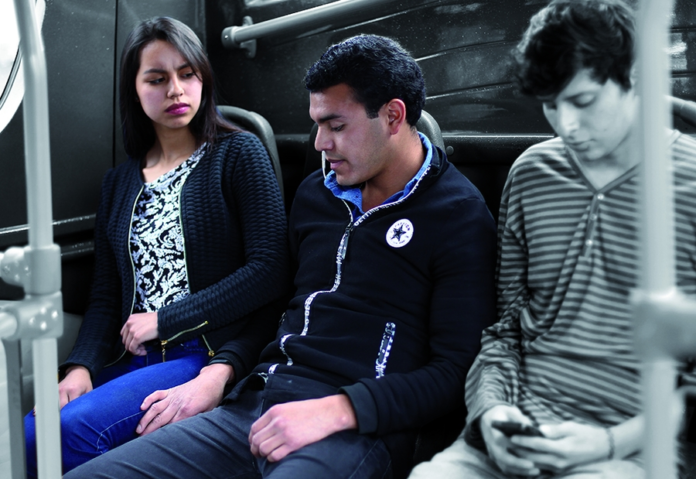 Mujer incómoda por situación de acoso en transporte público mientras un hombre invade su espacio personal