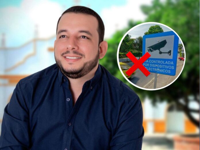 El alcalde Assad Raish Gámez junto a una señal de fotomultas en El Copey marcada con una X roja de rechazo.