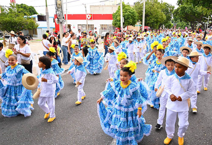 Grupos de niños bailando con trajes típicos azules y blancos en el Desfile de Piloneritos en el Festival Vallenato 2026 por la carrera Novena.