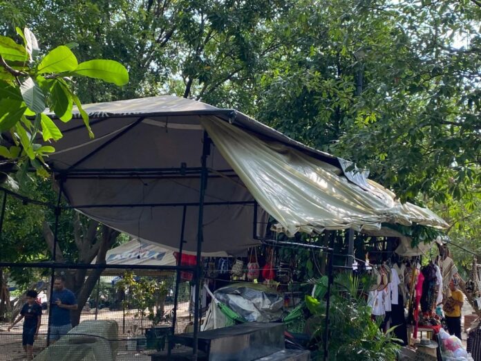 Primer plano del techo de una carpa comercial en la entrada del Balneario Hurtado Valledupar, mostrando lonas desgastadas, sucias, rotas y atadas de forma precaria, con artesanías colgadas debajo y vegetación de fondo. Evidencia el mal estado de la infraestructura.