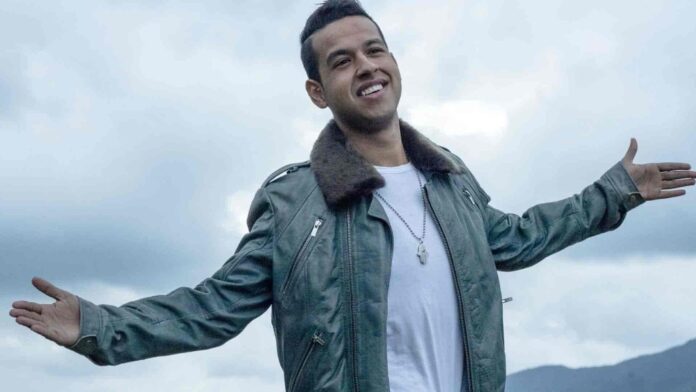 Martín Elías Díaz sonriendo con los brazos abiertos bajo un cielo nublado.