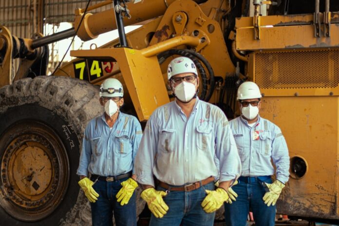 Equipo de trabajadores técnicos con equipo de protección personal frente a maquinaria minera en el Cesar.