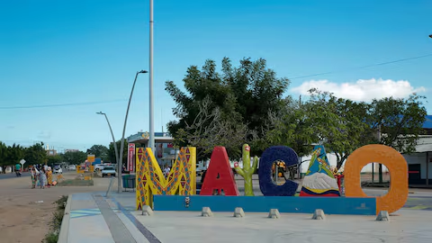 Entrada al municipio de Maicao, La Guajira, con letrero colorido y familia Wayúu.