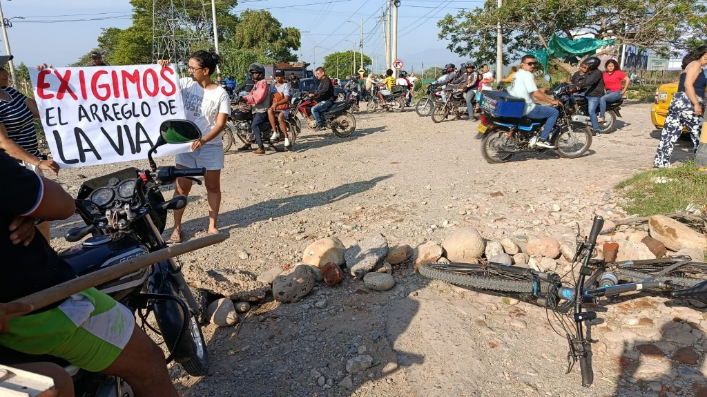 Primer plano de pancarta escrita a mano que dice "EXIGIMOS EL ARREGLO DE LA VIA" durante protesta contra la Alcaldía de Valledupar.