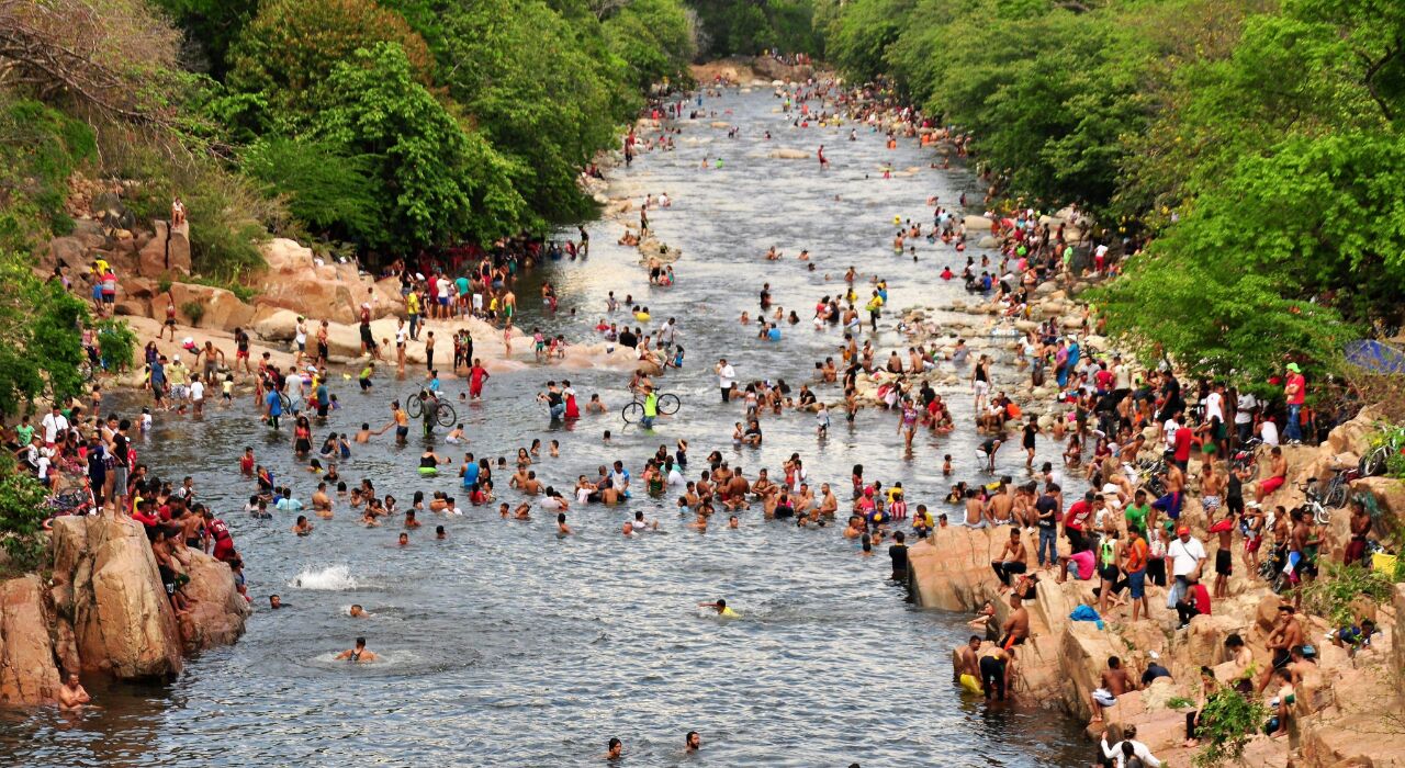 Vigilancia de la Policía Nacional en el Balneario Hurtado Valledupar durante el Festival Vallenato; se observa a un uniformado custodiando a los bañistas en el río Guatapurí cerca del puente metálico.