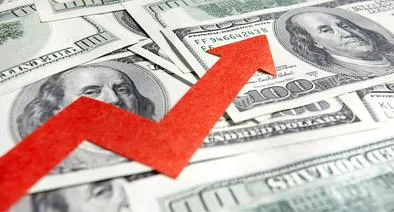 Gráfico de tendencia alcista con flecha roja sobre billetes de cien dólares que ilustra el comportamiento del dólar hoy en Colombia.