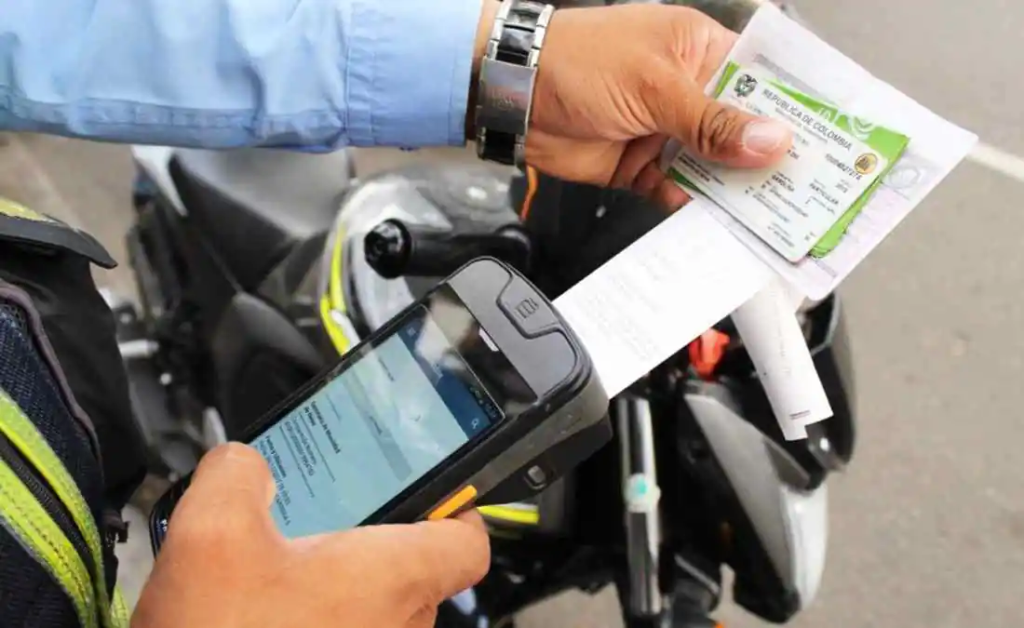 Conductor consulta comparendos y multas de tránsito desde un celular antes de realizar un trámite vehicular.