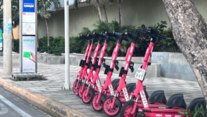 Fila de las nuevas patinetas rojas en Valledupar, disponibles para alquiler cerca de una parada de bus.